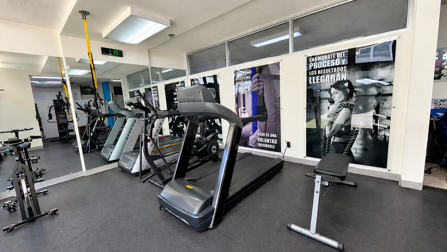Área de ejercicio de CAMI Fitness con caminadoras, bicicletas y espejos